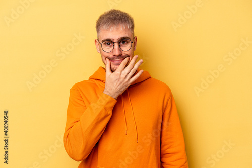 Young caucasian man isolated on yellow background doubting between two options. © Asier