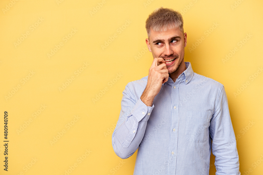 Young caucasian man isolated on yellow background relaxed thinking about something looking at a copy space. Young caucasian man isolated on yellow background relaxed thinking about something looking at a copy space.