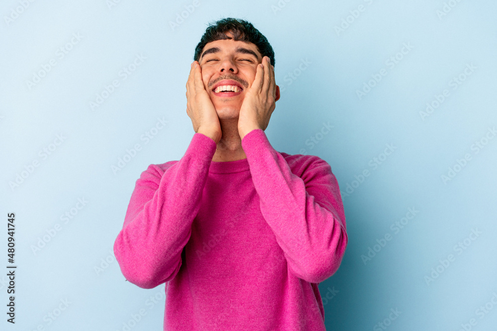 Young mixed race man isolated on blue background laughs joyfully keeping hands on head. Happiness concept. Young mixed race man isolated on blue background laughs joyfully keeping hands on head. Happiness concept.