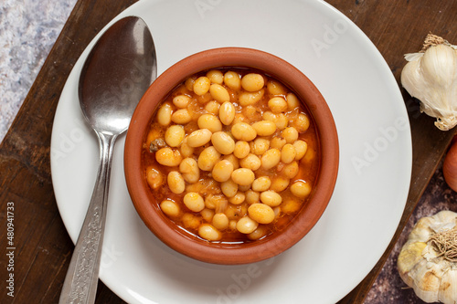 Hot turkish bean stew on wooden background. Ispir beans cooked in a casserole - Kuru Fasulye. Top view
