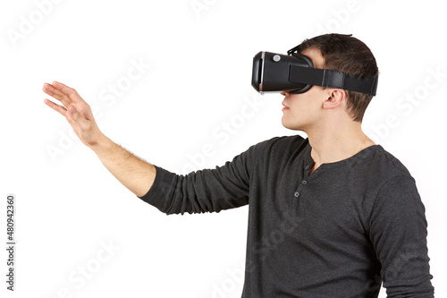 A young man with a virtual reality helmet on his head pulls his hand forward. The figure is isolated on a white background.