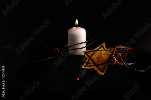 Holocaust memory day. Arbed wire and burning candle on black background
