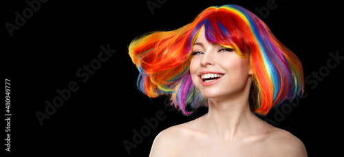 Woman hair as color splash. Rainbow up do short haircut. Beautiful young girl model with glowing  healthy skin on a black background photo