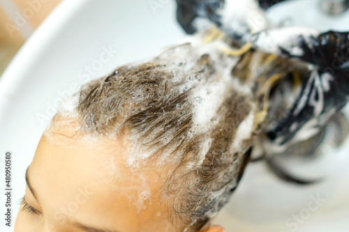 The girl is washed her hair in the salon. Shampoo bubbles close up