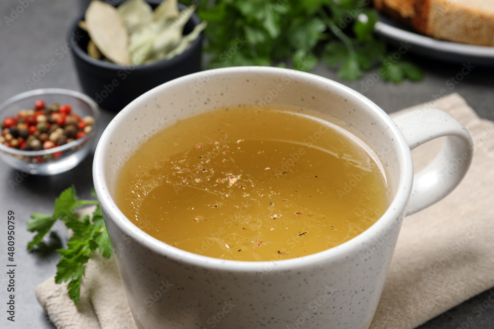 Hot delicious bouillon in cup on table, closeup Hot delicious bouillon in cup on table, closeup