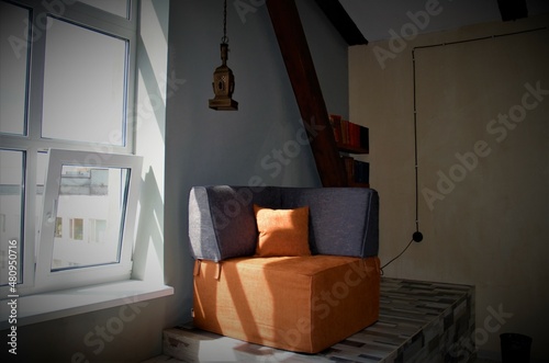 design of part of the room. Near the window is an armchair in orange gray color