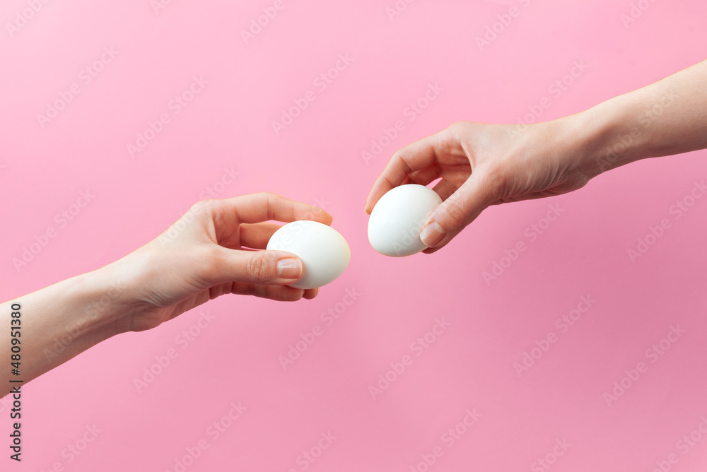 Woman hands holding Easter eggs for knocking on pink background. Easter celebration or creative concept. Adam creation Woman hands holding Easter eggs for knocking on pink background. Easter celebration or creative concept. Adam creation