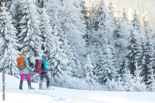 Two women walk in snowshoes in the snow