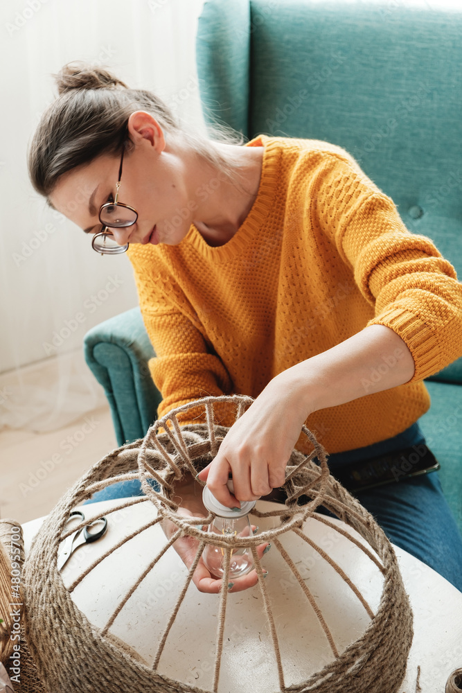 Woman makes handmade diy lamp from jute rope Stock Photo
