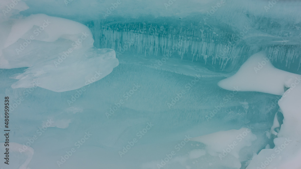 The texture of ice. Close-up. Full screen. Columns of bubbles of frozen methane gas are visible in the depths. Patches of snow on a turquoise smooth surface. Baikal