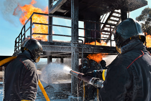Dos bomberos apagando un peligroso fuego en una fábrica