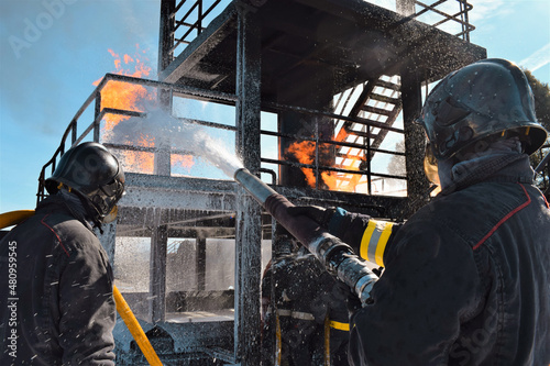 Bomberos apagando el fuego producido en una infraestructura metálica photo