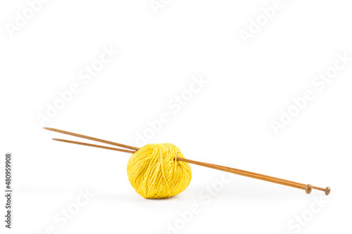 Un ovillo de lana amarilla con dos agujas de madera para tejer sobre un fondo blanco liso y aislado. Vista de frente y de cerca. Copy space