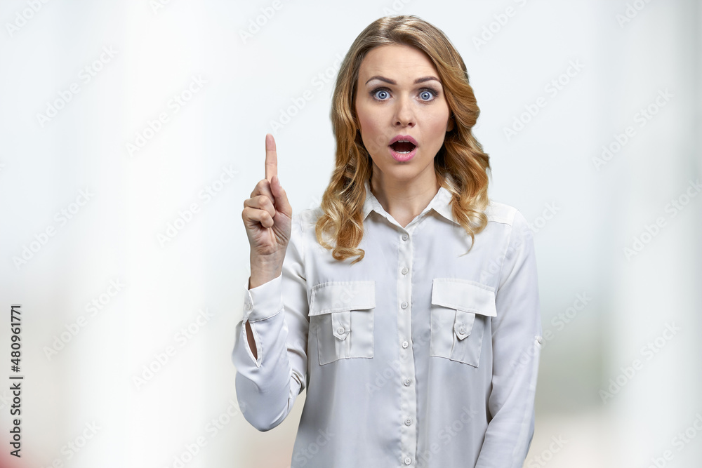 Young energetic woman pointing her finger up standing on white background. Young energetic woman pointing her finger up standing on white background.