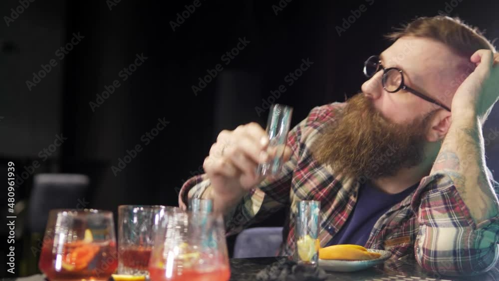 A very drunk young man is lying with his head on a table in a bar. A drunk man in depression sleeps, wakes up and drinks a glass. There are a lot of empty glasses on the table next to the client. A very drunk young man is lying with his head on a table in a bar. A drunk man in depression sleeps, wakes up and drinks a glass. There are a lot of empty glasses on the table next to the client.
