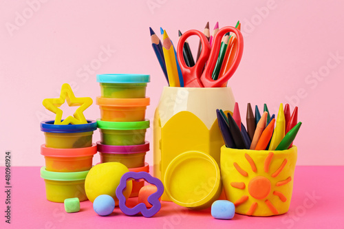 Set of bright play dough with tools and pencils on color background