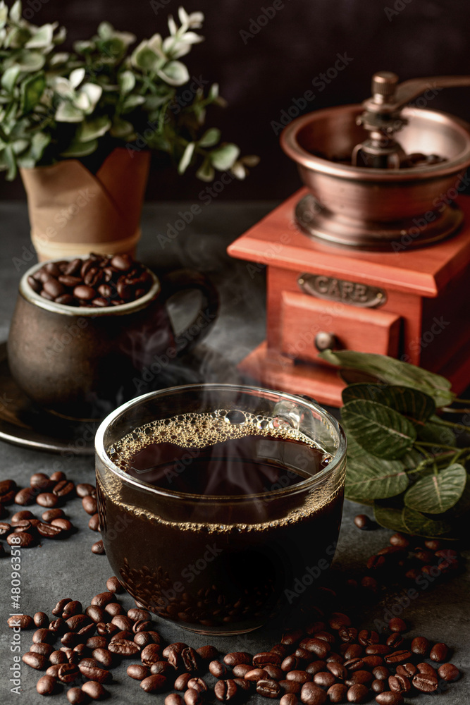 Glass of coffee on table with beans and manual mill Glass of coffee on table with beans and manual mill