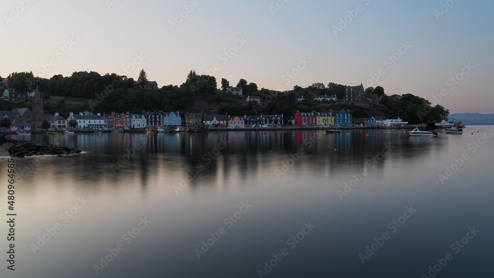 Dusk and a calm sea with colourful painted houses around the harbour of Tobermory on the Isle of Mull, Hebrides, Scotland, UK