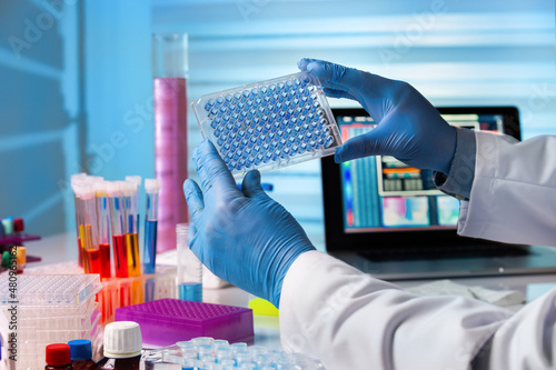 Canvas Print Researcher in lab holding a 96 well plate with biological samples for analysis