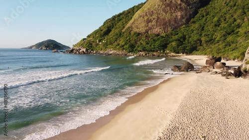 Aerial view of Prainha Beach, a paradise in the west side of Rio de Janeiro, Brazil. Big hills around. Sunny day at dawn. Greenish sea. Drone take.