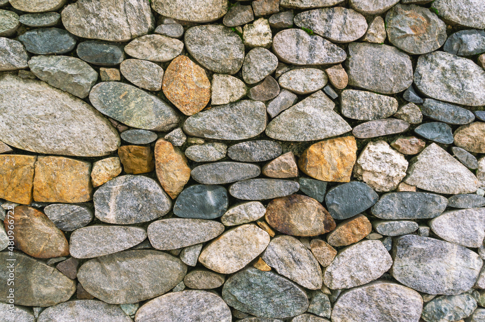 Background of stones. A wall of multicolored stones. The masonry is made of untreated stones. A wall of large stones. Background of stones. A wall of multicolored stones. The masonry is made of untreated stones. A wall of large stones.
