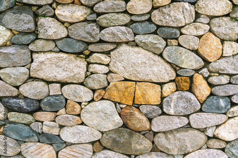 Background of stones. A wall of multicolored stones. The masonry is made of untreated stones. A wall of large stones. Background of stones. A wall of multicolored stones. The masonry is made of untreated stones. A wall of large stones.