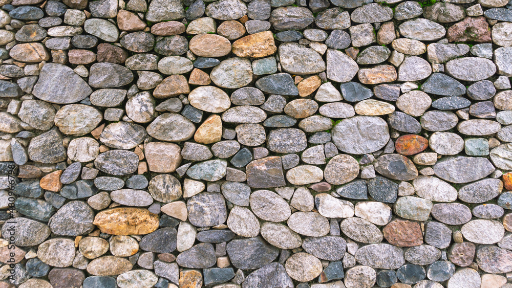 Background of stones. A wall of multicolored stones. The masonry is made of untreated stones. A wall of large stones. Background of stones. A wall of multicolored stones. The masonry is made of untreated stones. A wall of large stones.