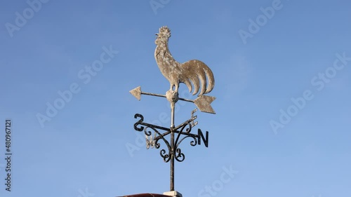 Cockerel weather vane moving in a light breeze against a blue sky. Aldeburgh, Suffolk, UK photo