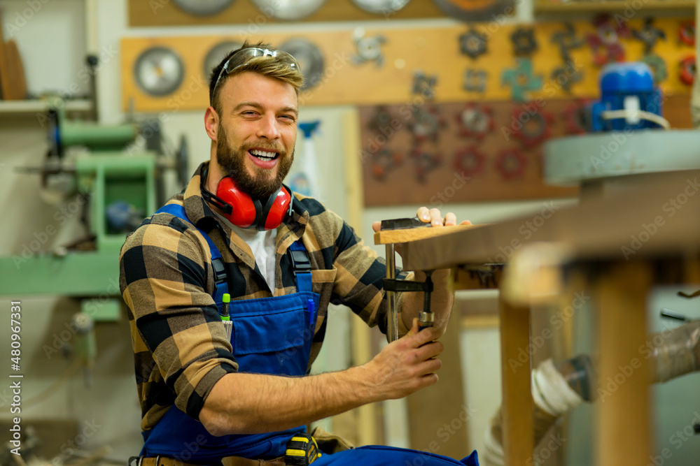 Young handsome caucasian carpenter working while posing for camera Young handsome caucasian carpenter working while posing for camera