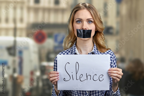 Young woman activist holding banner with handwritten inscription Silence. © DenisProduction.com