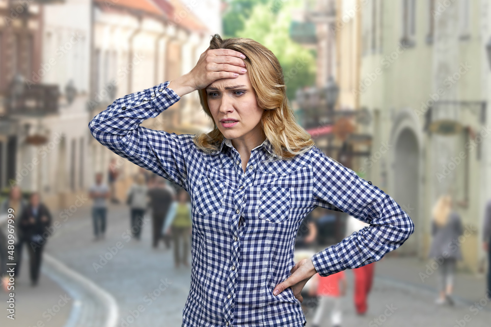 Fototapeta premium Young worried stressed woman standing on blur city street.