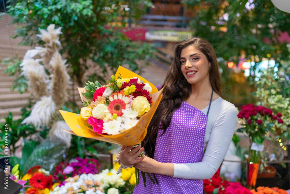 A proud and beautiful and smiling florist shows the bouquet she made