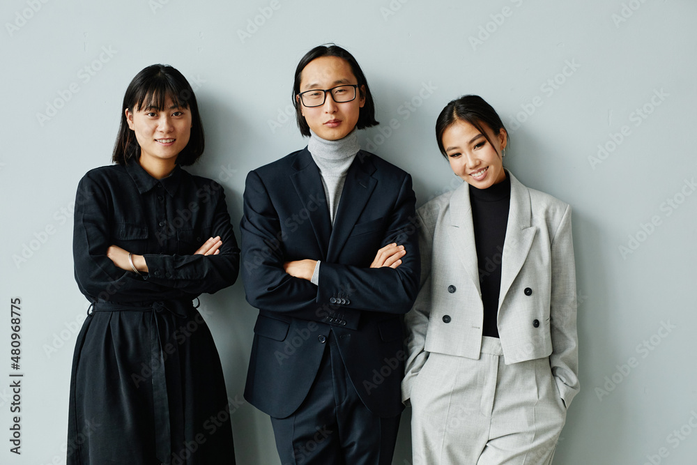 Waist up portrait of Asian business team smiling at camera against miniman background Waist up portrait of Asian business team smiling at camera against miniman background