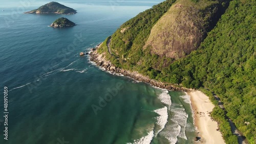 Aerial view of Prainha Beach, a paradise in the west side of Rio de Janeiro, Brazil. Big hills around. Sunny day at dawn. Greenish sea. Drone take.