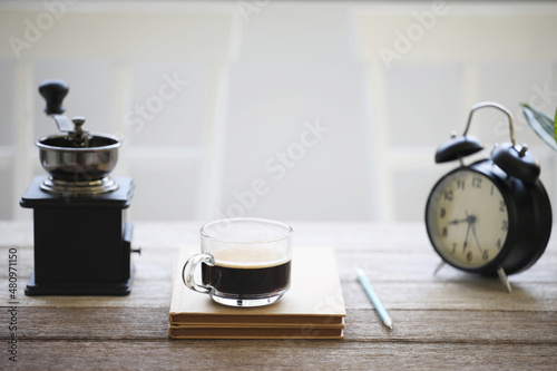 Coffee glass cup and old book and clock on wooden table
