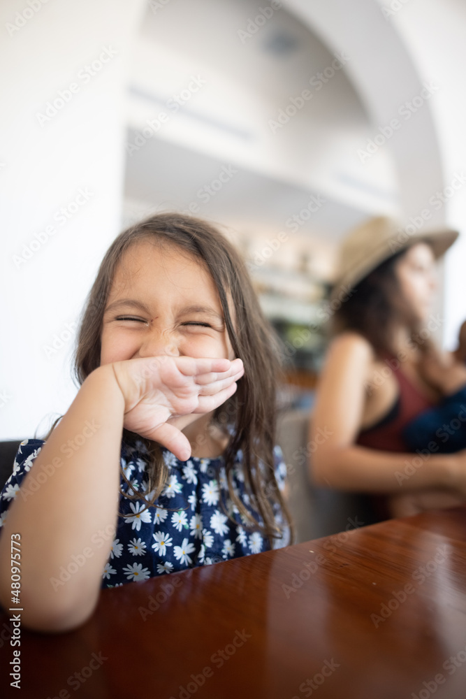 Cute little girl covering her smile with the back of her hand Cute little girl covering her smile with the back of her hand