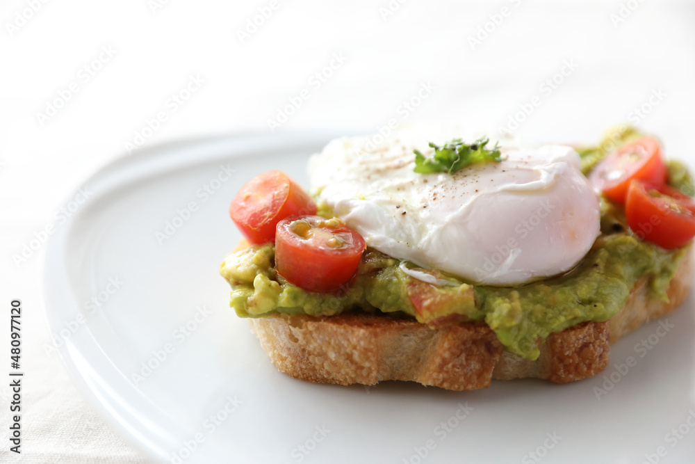 Poached eggs with avocado on toast in white background