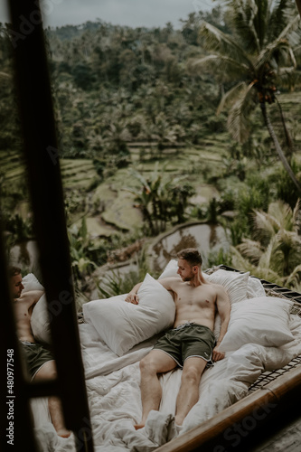 Young male traveller relaxing in a hotel in Bali, surrounded by nature, palm trees, rice fields and jungle views in Ubud, Indonesia, Asia