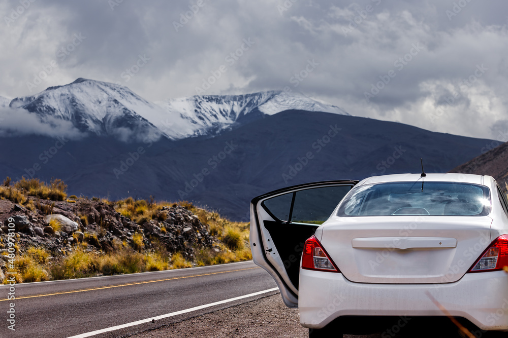 Naklejka premium Car stopped on the side of the road in Salta, Argentina, with the Nevado de Acay hill in the background