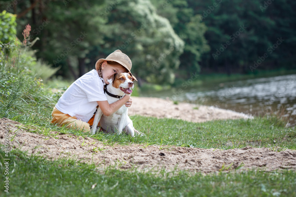 Cute girl hugging Jack Russell Terrier dog sitting at park in sunny summer day. Cute girl hugging Jack Russell Terrier dog sitting at park in sunny summer day.