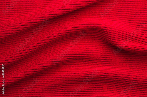 Knitted bright red fabric, ribbing texture with large folds