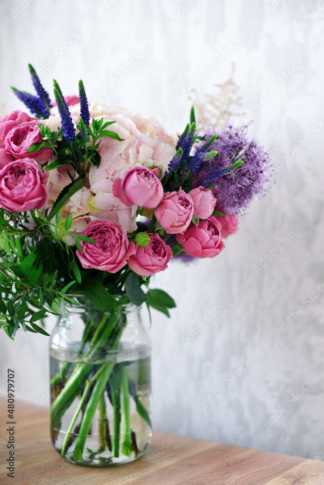 Flowers in a glass jar on grey concrete background. Vintage home decor. Flowers in a glass jar on grey concrete background. Vintage home decor.