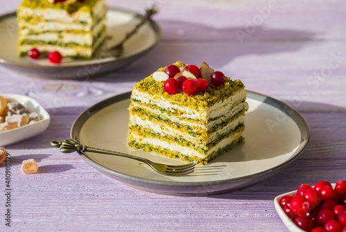 Dessert, sliced spinach cake with sour cream or cream cheese cream on a ceramic plate on a purple wooden background. Dessert recipes.