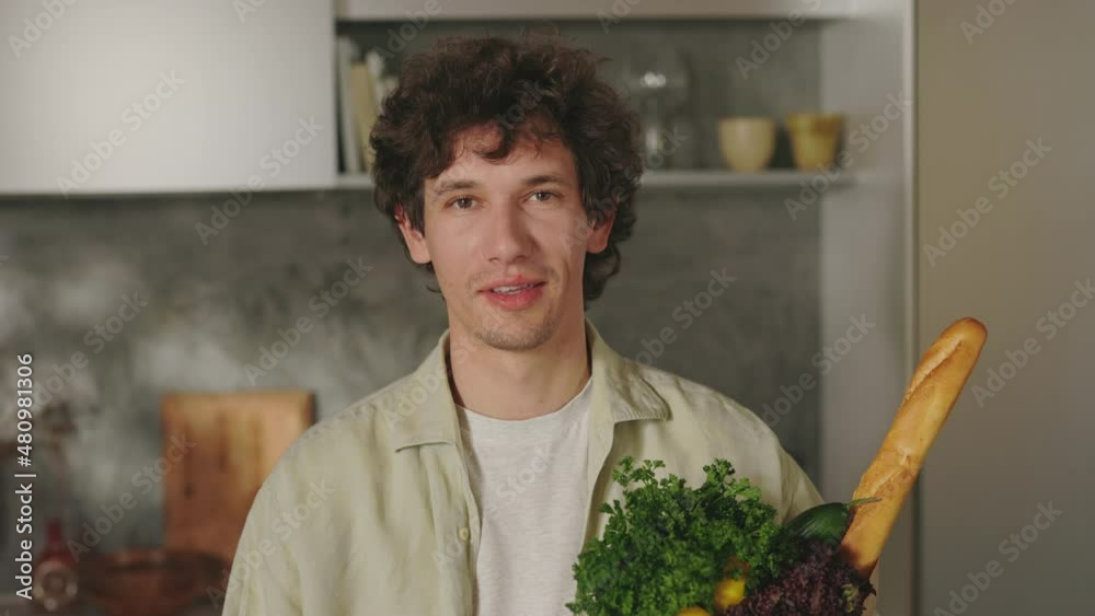 Handsome man standing on kitchen with grocery bag