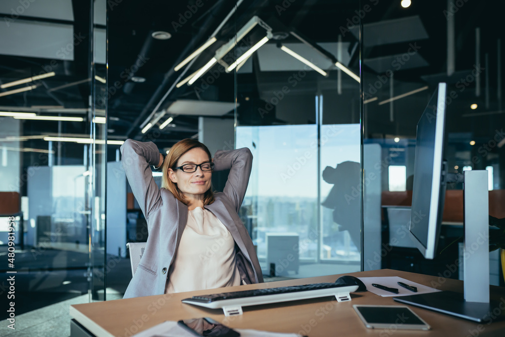 business owner woman resting during working hours puts her hands behind her head, thinks about business plans, works in a modern office business owner woman resting during working hours puts her hands behind her head, thinks about business plans, works in a modern office