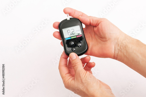 Close-up of the hands of a woman using a glucose meter to measure blood sugar isolated on a white background. Checking blood sugar level by glucometer for diabetes testing. High result, above the norm photo