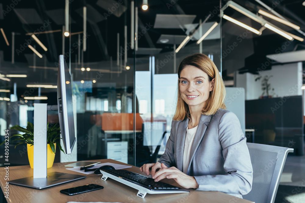 © Liubomir - Happy and successful business woman working in the office at the computer rejoices in good results, successful employee and boss