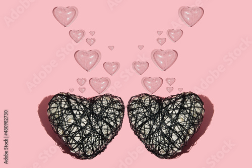 Two wire hearts with plastic translucent hearts as bubbles on pastel grey background. Minimalist Valentine's day concept. photo