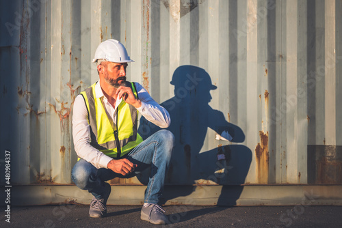 Portrait images of Caucasian engineer man Sitting on the floor and thinking about planning, with containers background, to people and worker concept.