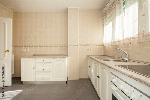 Kitchen with white cabinets  pink granite countertop tiled with cream tiles and border